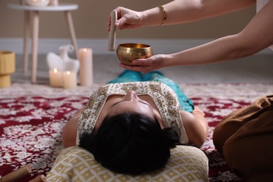 Photo of Woman undergoing singing bowl therapy lying on floor indoors