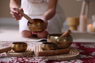 Photo of Woman with singing bowls and burning candles indoors, closeup