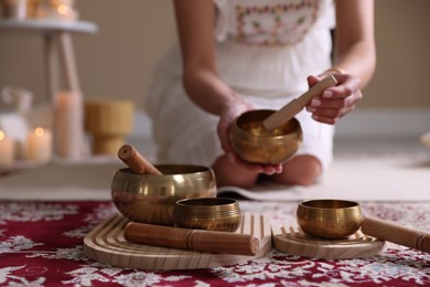 Photo of Woman with singing bowls and burning candles indoors, closeup