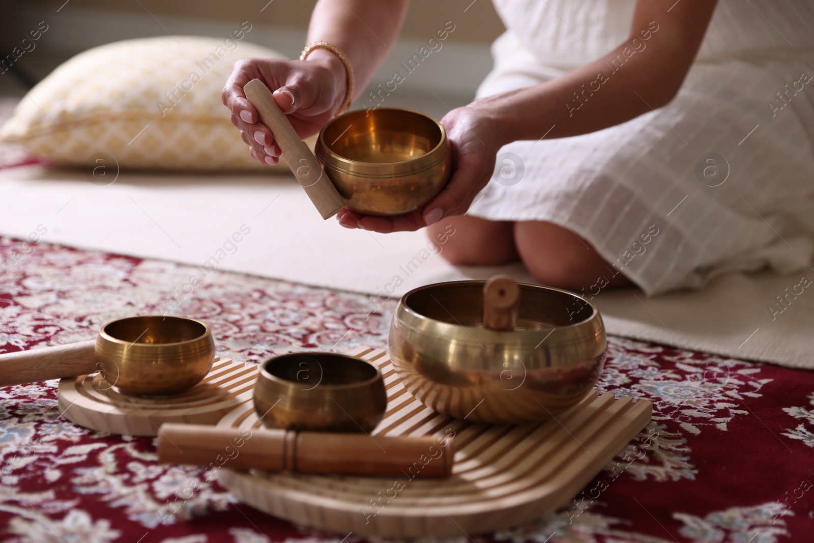 Photo of Woman with singing bowls on floor indoors, closeup