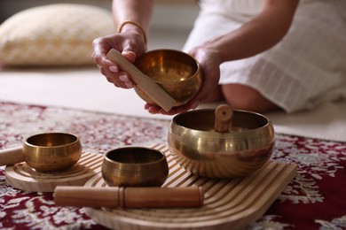 Photo of Woman with singing bowls on floor indoors, closeup