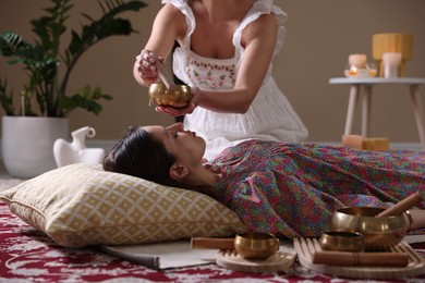 Woman undergoing singing bowl therapy lying on floor indoors