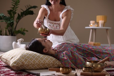 Photo of Woman undergoing singing bowl therapy lying on floor indoors