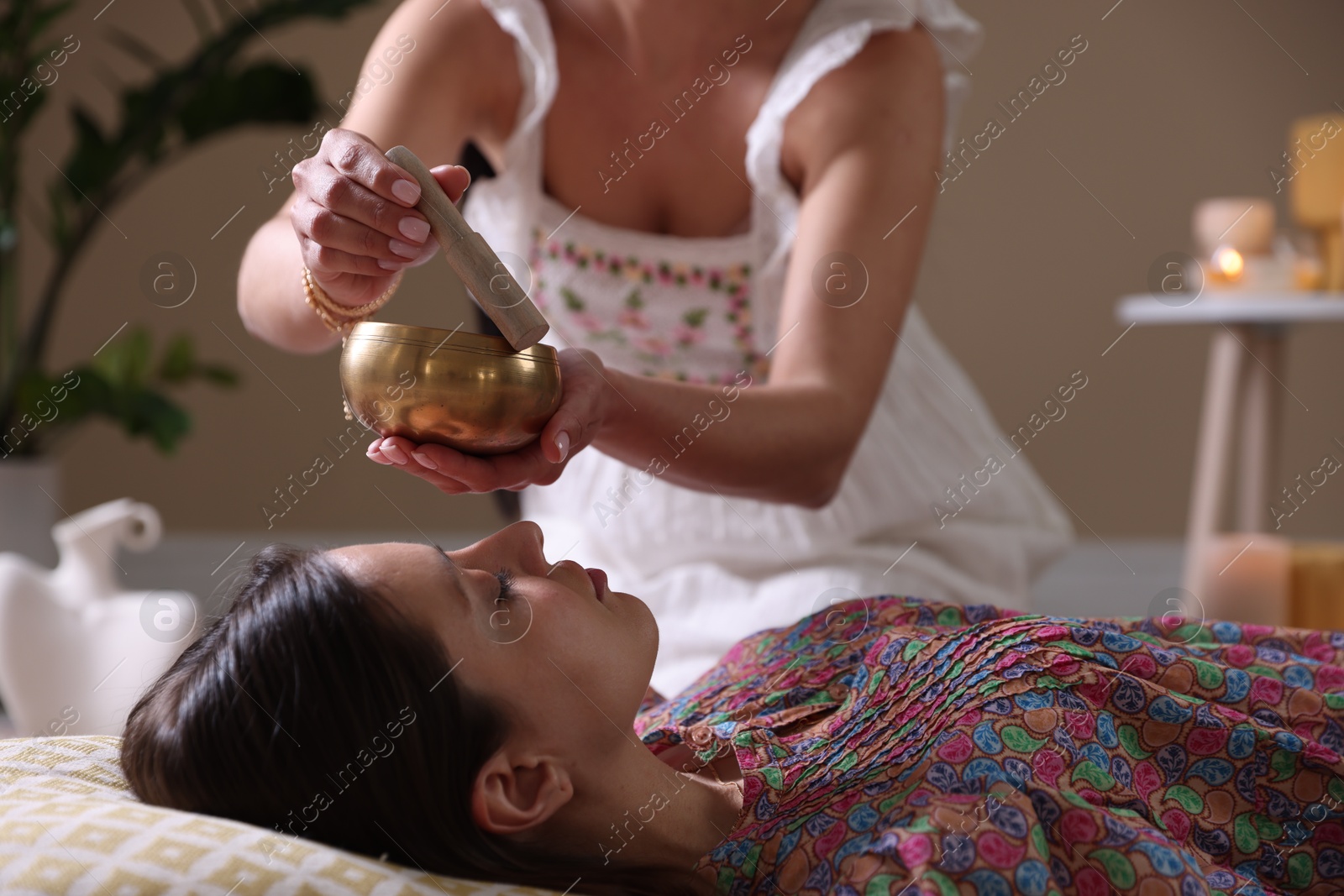 Photo of Woman undergoing singing bowl therapy lying on floor indoors