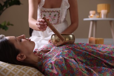 Woman undergoing singing bowl therapy lying on floor indoors