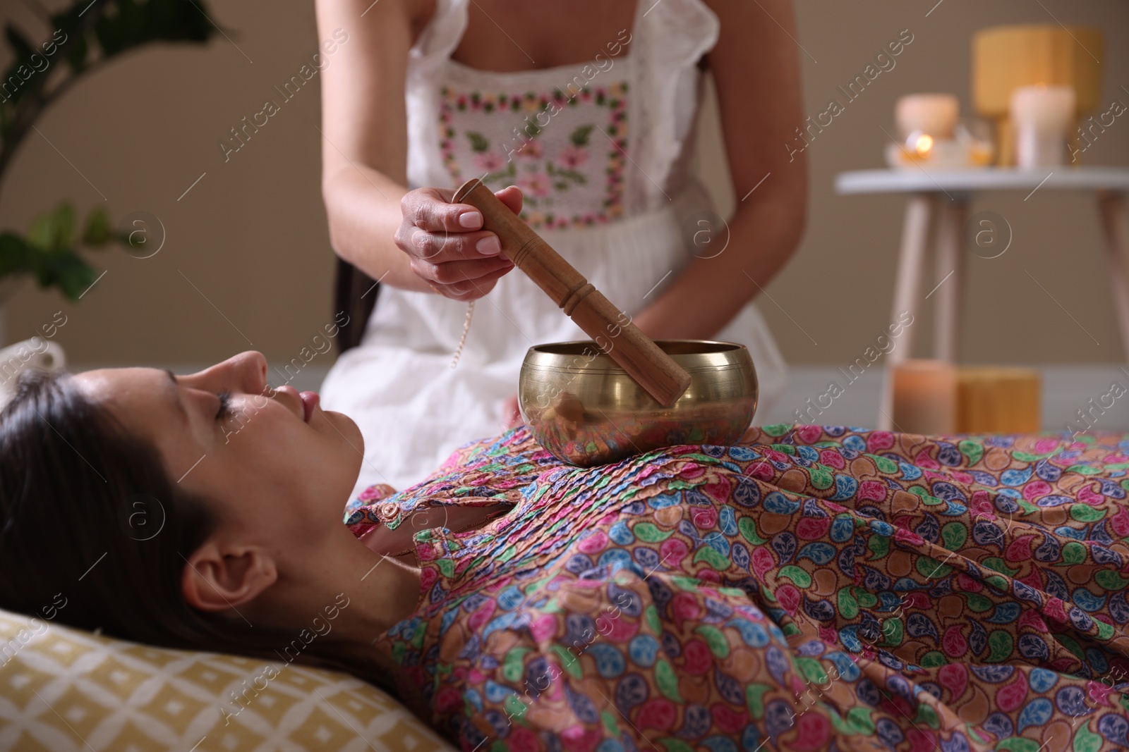 Photo of Woman undergoing singing bowl therapy lying on floor indoors