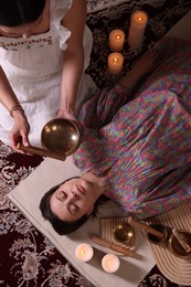 Woman undergoing singing bowl therapy indoors, top view