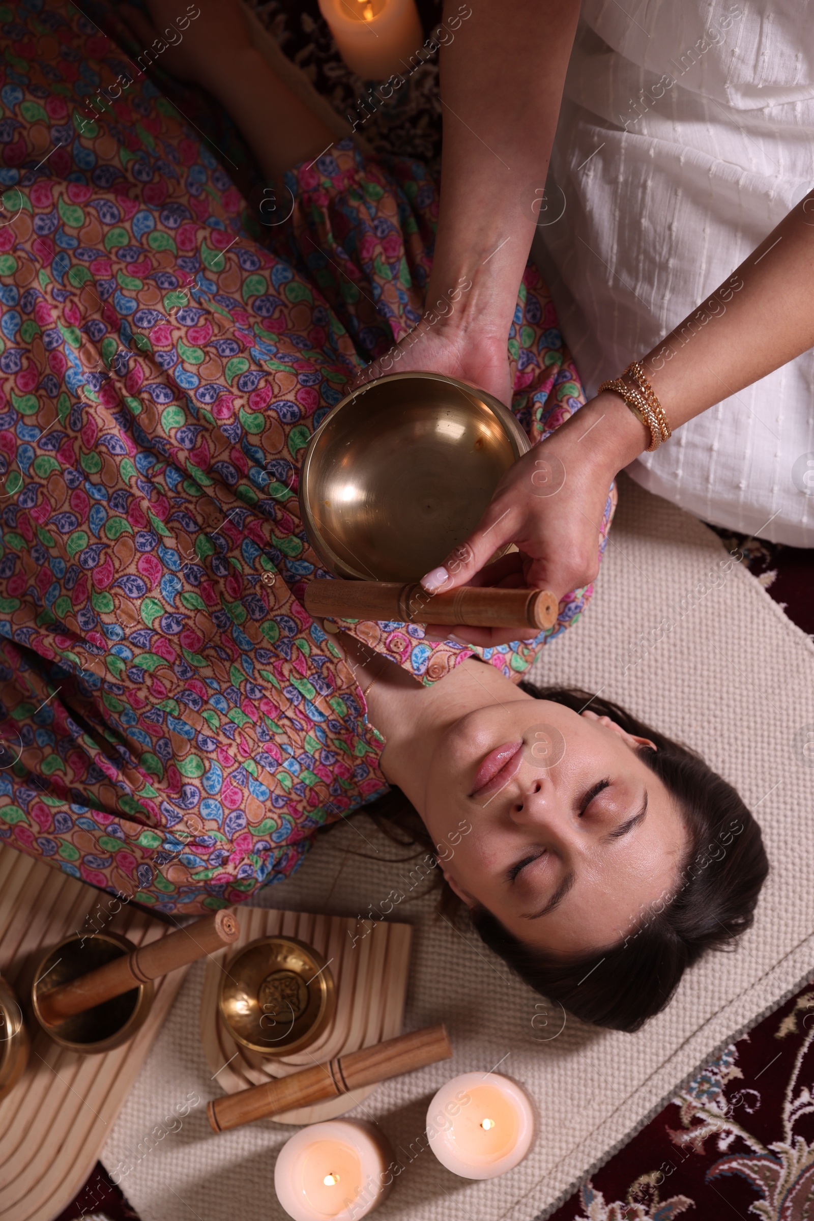 Photo of Woman undergoing singing bowl therapy indoors, top view