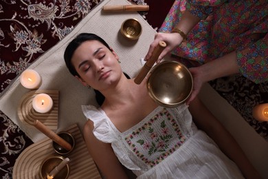 Photo of Woman undergoing singing bowl therapy indoors, top view