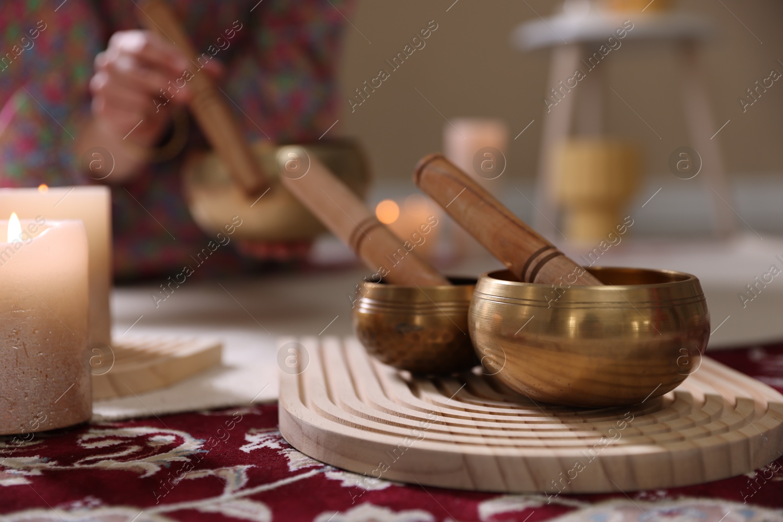 Photo of Woman with singing bowls and burning candles indoors, closeup