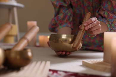 Photo of Woman with singing bowls and burning candles indoors, closeup