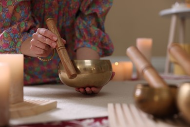 Photo of Woman with singing bowls and burning candles indoors, closeup