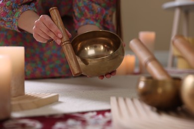 Photo of Woman with singing bowls and burning candles indoors, closeup