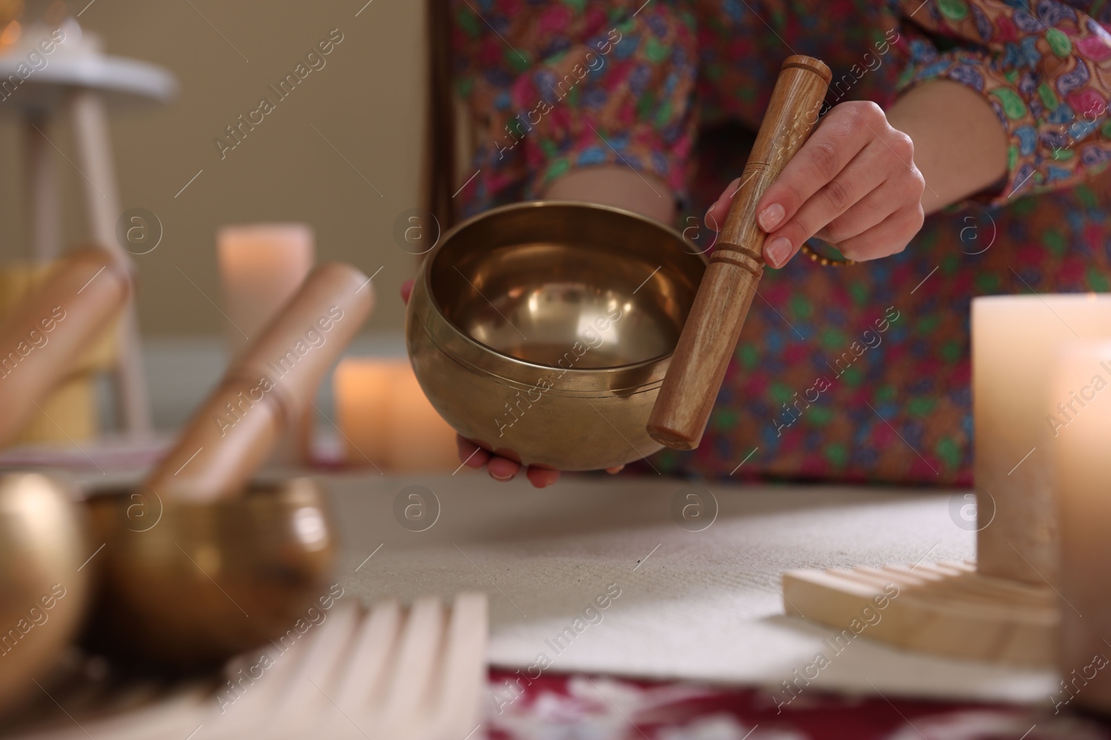 Photo of Woman with singing bowls and burning candles indoors, closeup