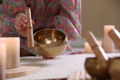 Photo of Woman with singing bowls and burning candles indoors, closeup