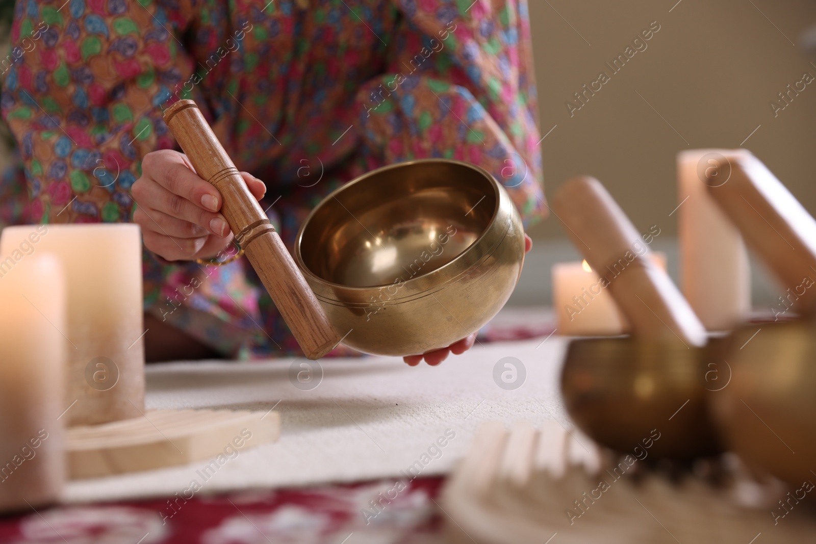 Photo of Woman with singing bowls and burning candles indoors, closeup