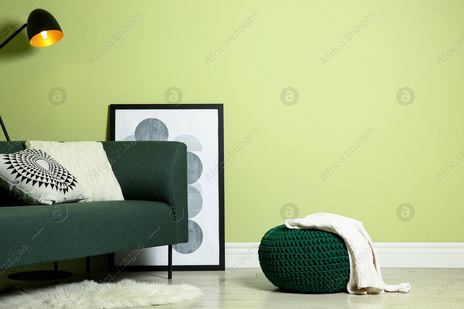 Photo of Stylish living room interior with comfortable knitted pouf and sofa near light green wall