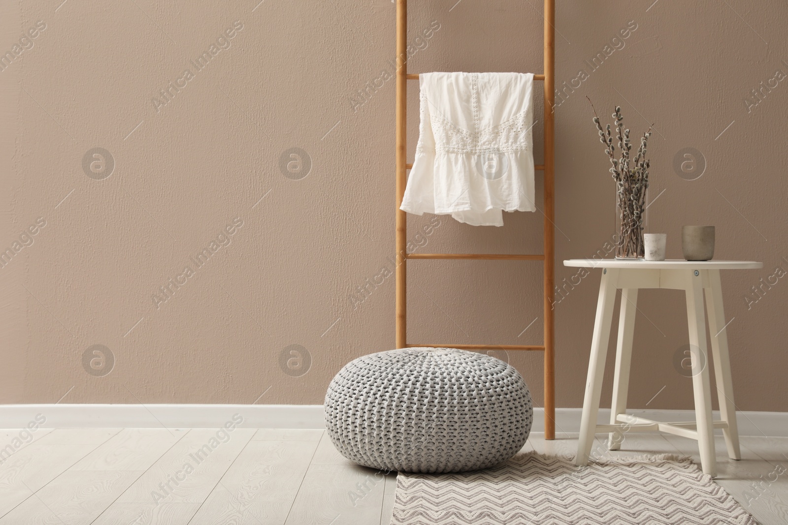 Photo of Stylish room interior with pouf, ladder and decor elements. Space for text