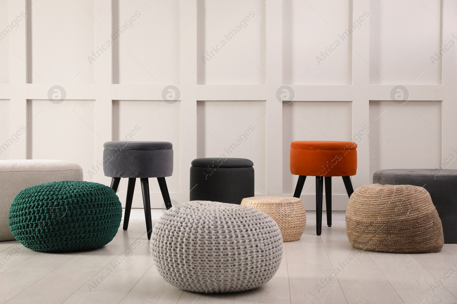 Photo of Different stylish poufs and ottomans near light wall