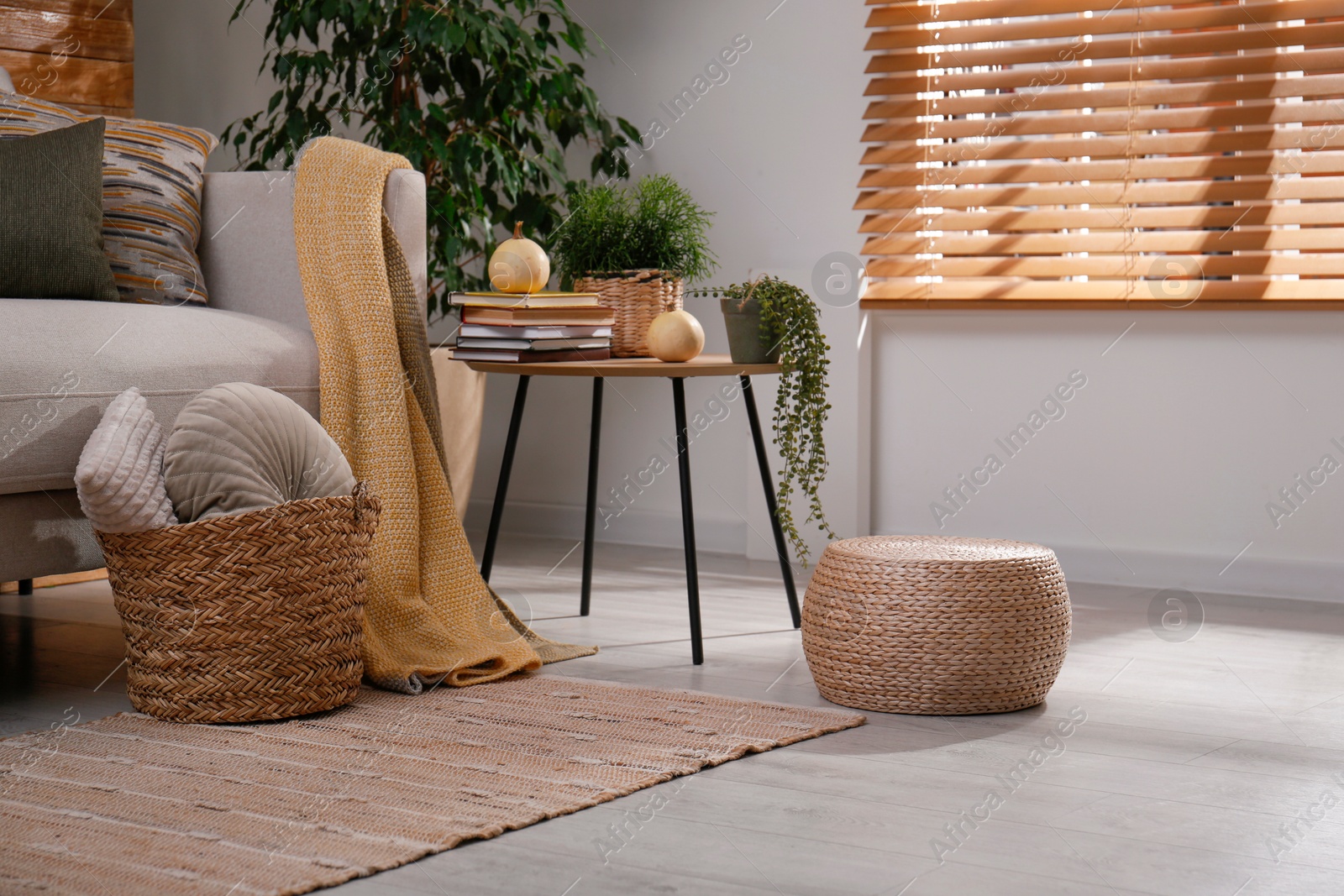 Photo of Stylish living room interior with comfortable sofa and wicker pouf