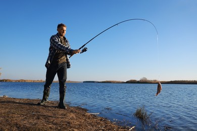 Photo of Fisherman catching fish with rod at riverside