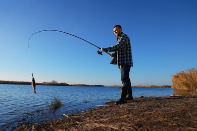 Photo of Fisherman catching fish with rod at riverside