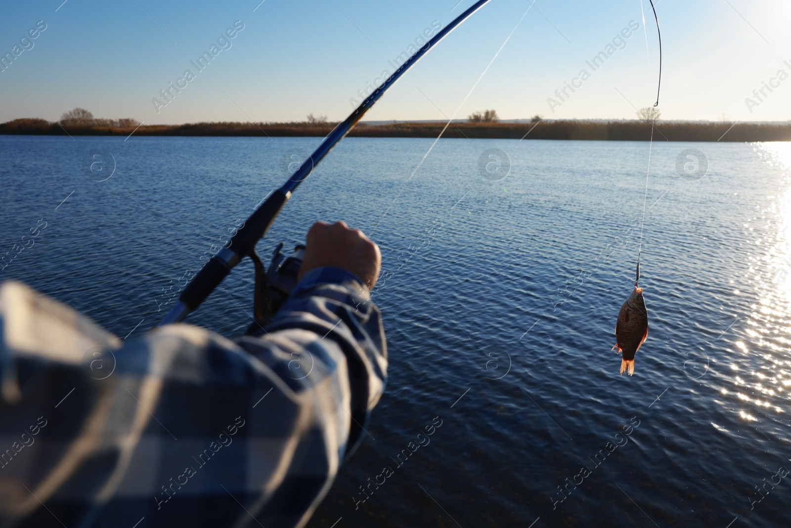 Photo of Fisherman catching fish with rod at riverside, closeup