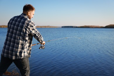 Photo of Fisherman with rod fishing at riverside. Recreational activity