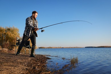 Photo of Fisherman with rod fishing at riverside. Recreational activity