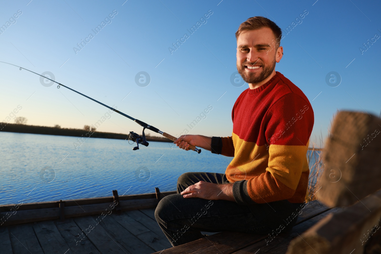 Photo of Fisherman with fishing rod at riverside on sunny day