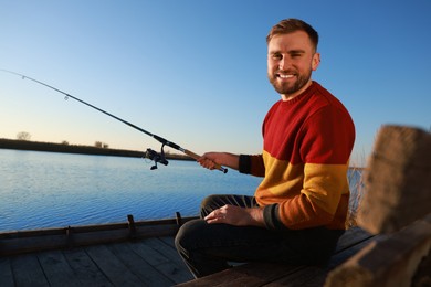 Photo of Fisherman with fishing rod at riverside on sunny day