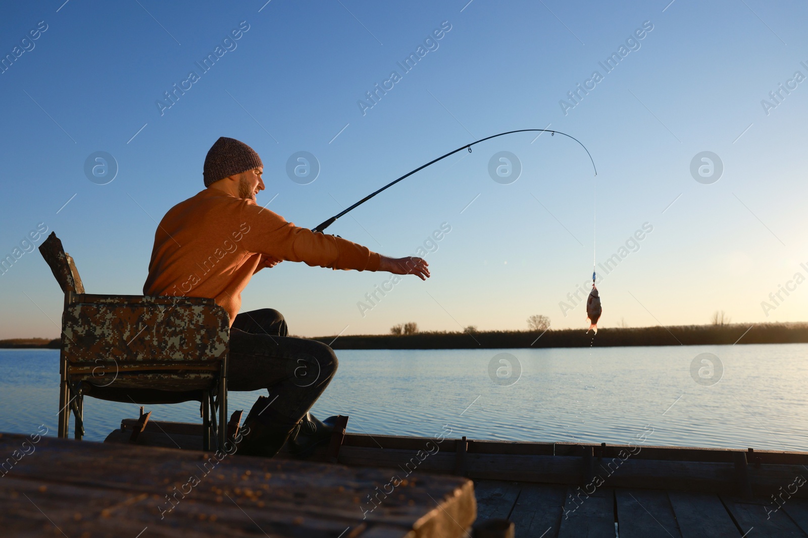 Photo of Fisherman catching fish with rod at riverside