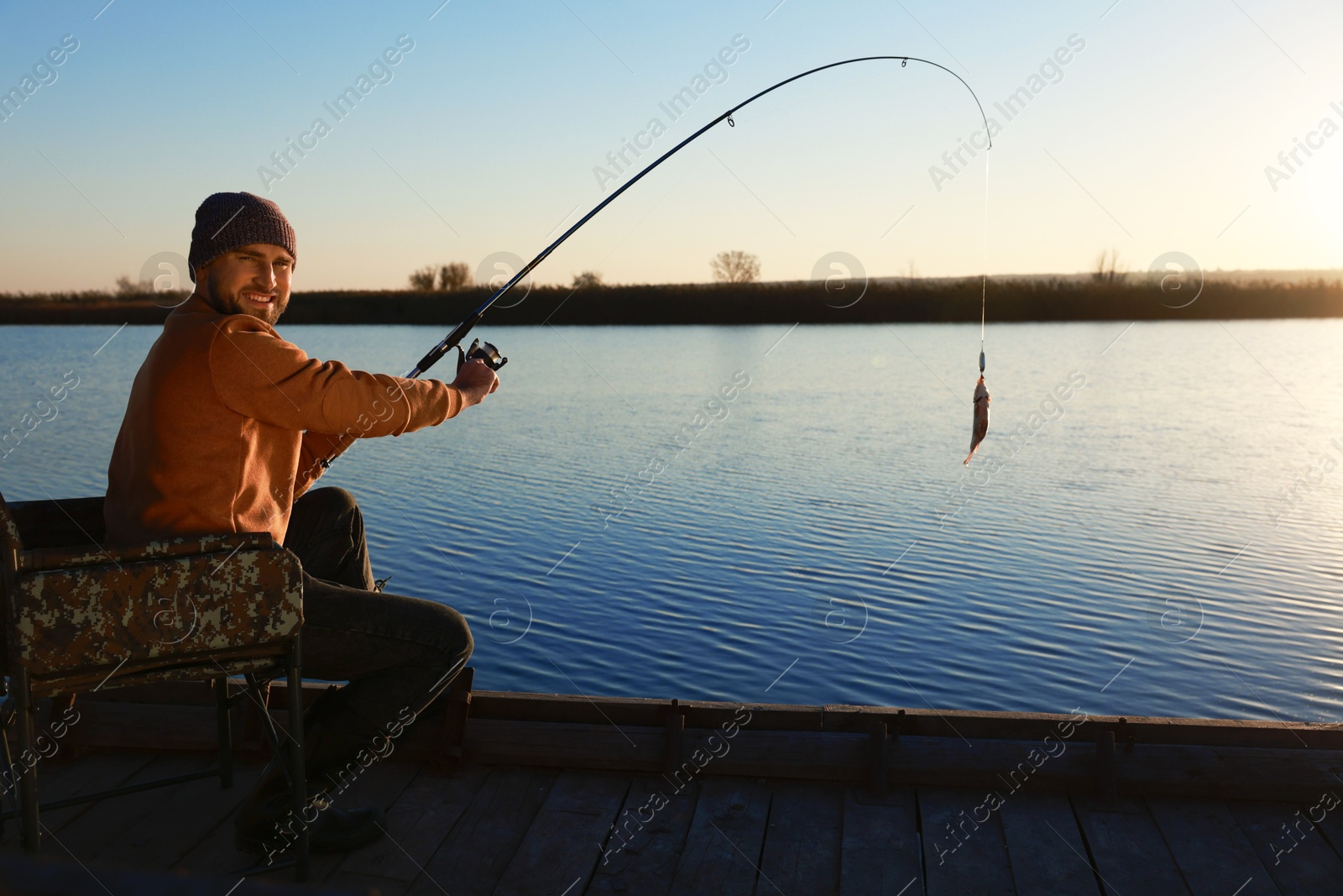 Photo of Fisherman catching fish with rod at riverside