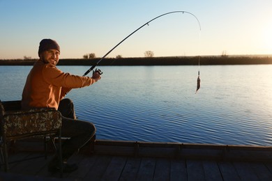 Photo of Fisherman catching fish with rod at riverside