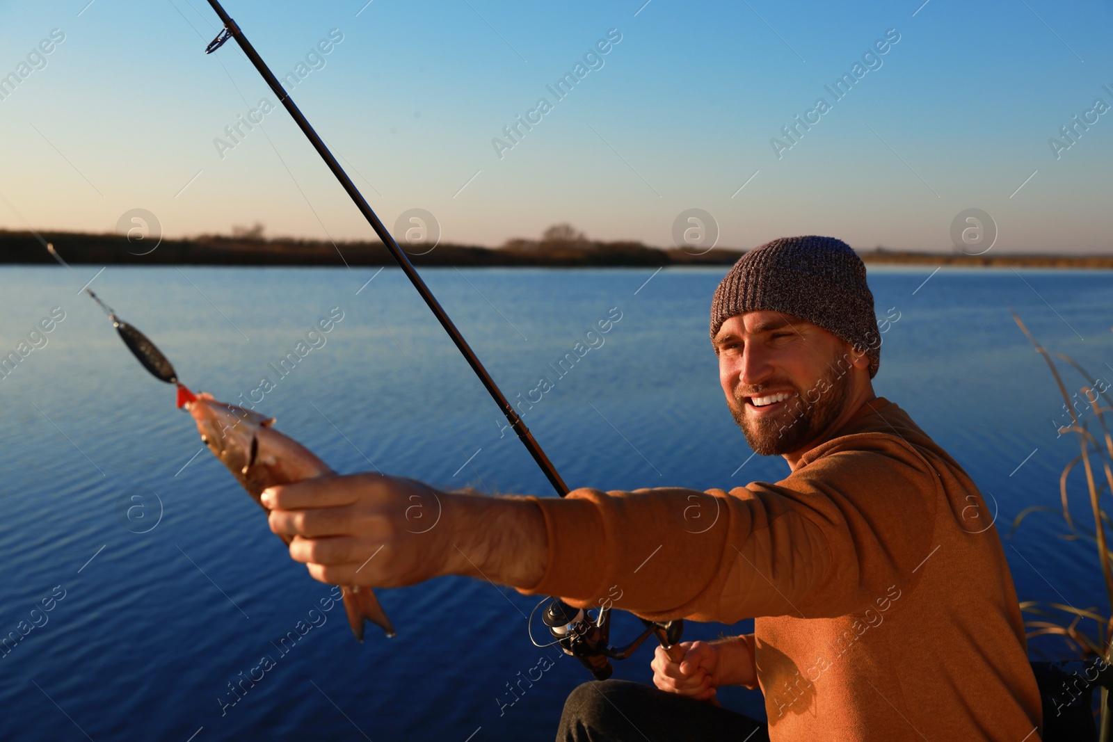 Photo of Fisherman with rod and caught fish at riverside