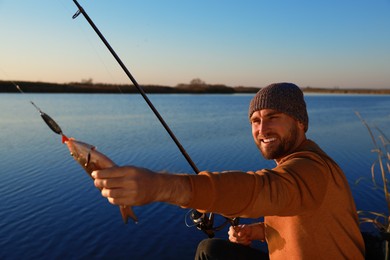 Photo of Fisherman with rod and caught fish at riverside