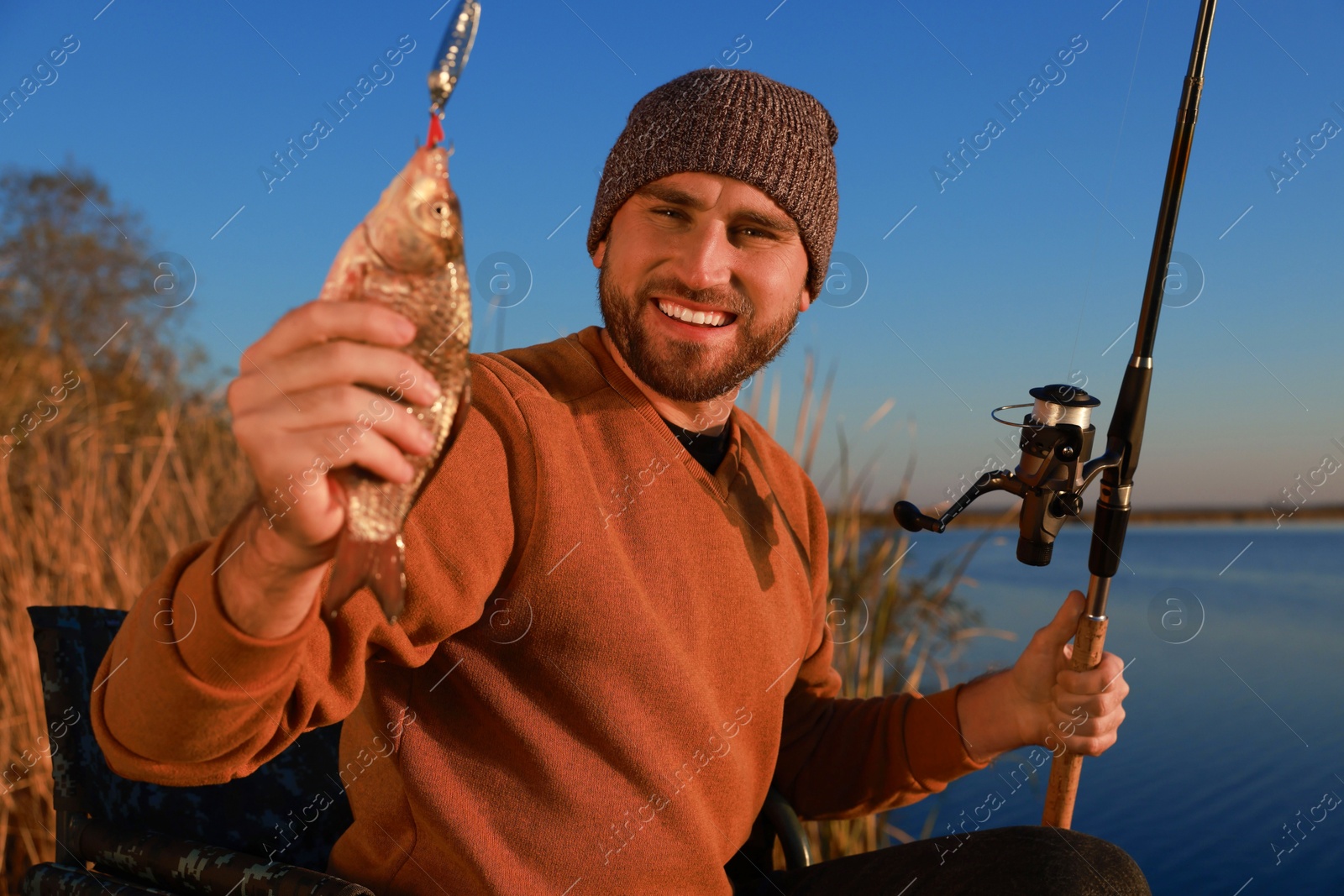 Photo of Fisherman with rod and caught fish at riverside