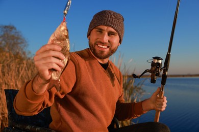 Photo of Fisherman with rod and caught fish at riverside