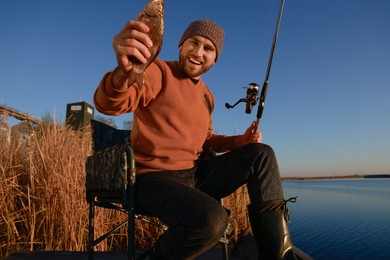 Photo of Fisherman with rod and caught fish at riverside