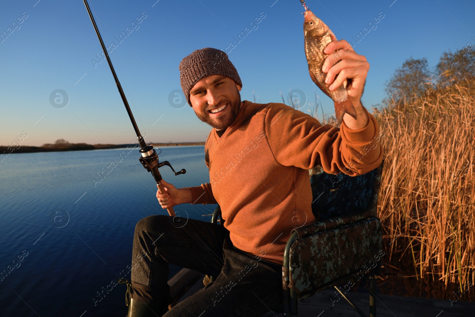 Photo of Fisherman with rod and caught fish at riverside