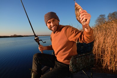 Photo of Fisherman with rod and caught fish at riverside