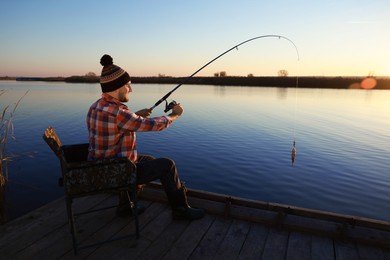 Fisherman catching fish with rod at riverside