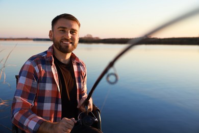 Photo of Fisherman with fishing rod at riverside. Recreational activity