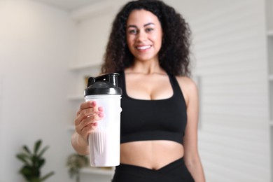 Photo of Beautiful woman with protein shake at home, selective focus