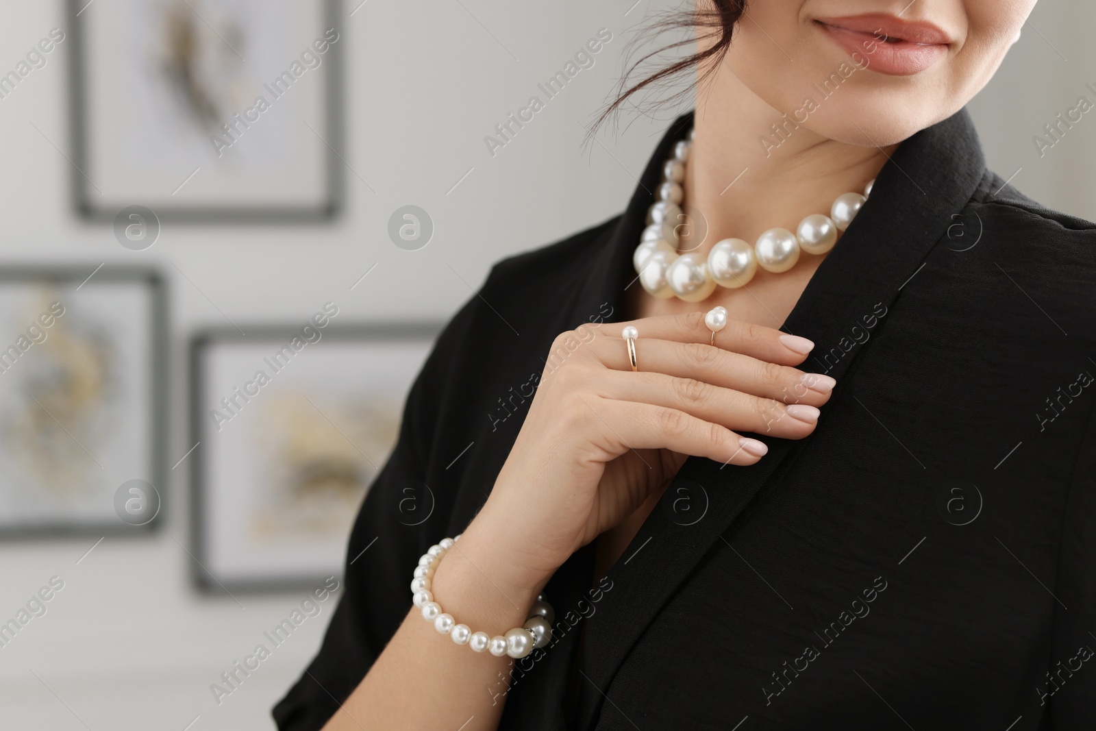 Photo of Young woman wearing elegant pearl jewelry indoors, closeup. Space for text