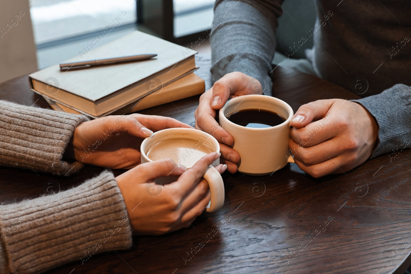 Photo of Colleagues having coffee break at wooden table in cafe, closeup