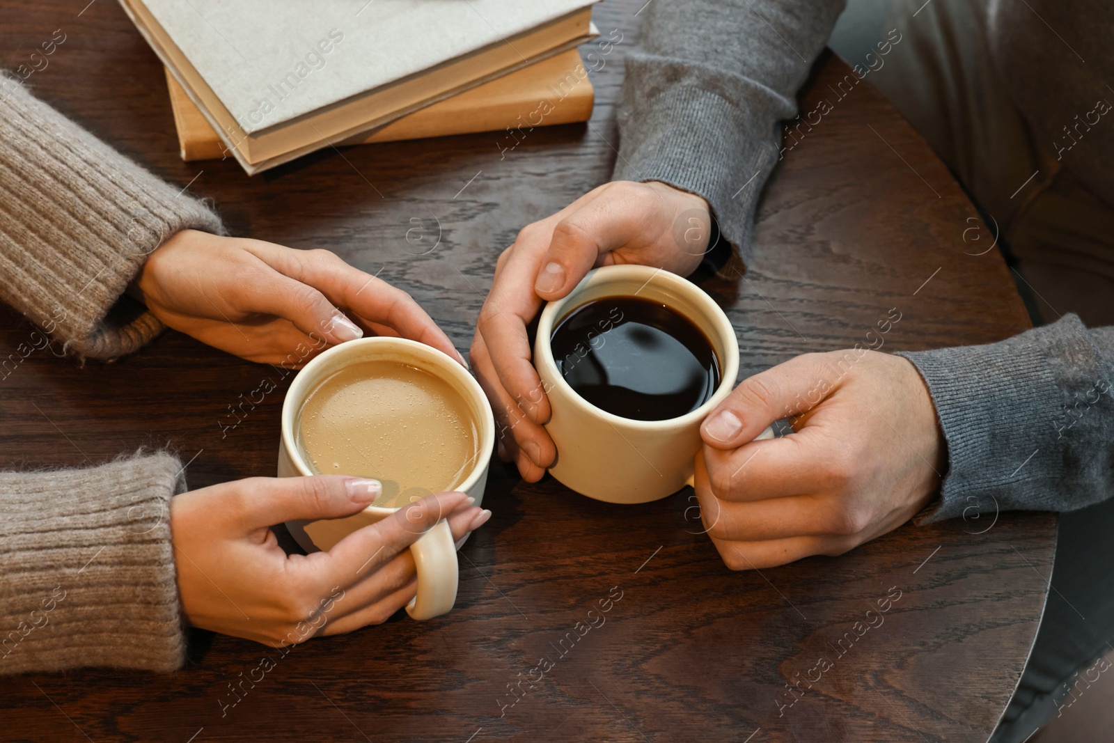 Photo of Colleagues having coffee break at wooden table, closeup