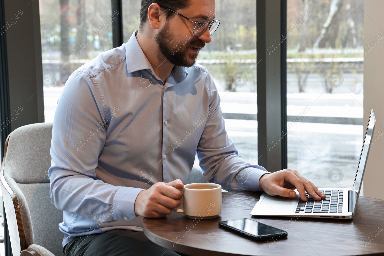 Photo of Businessman having coffee break at wooden table in cafe