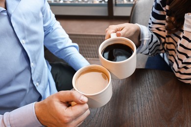 Photo of Colleagues having coffee break at wooden table in cafe, closeup