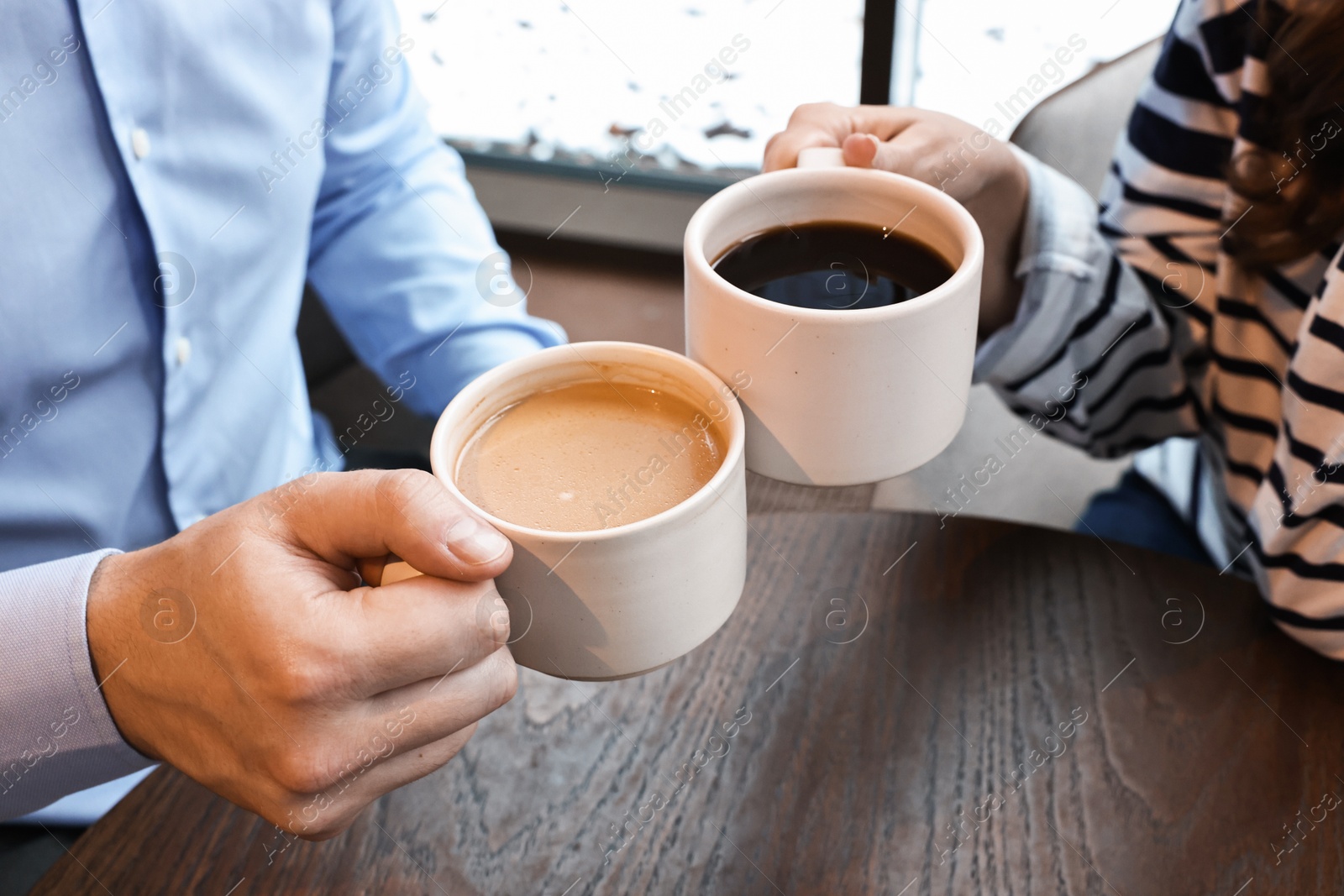 Photo of Colleagues having coffee break at wooden table in cafe, closeup